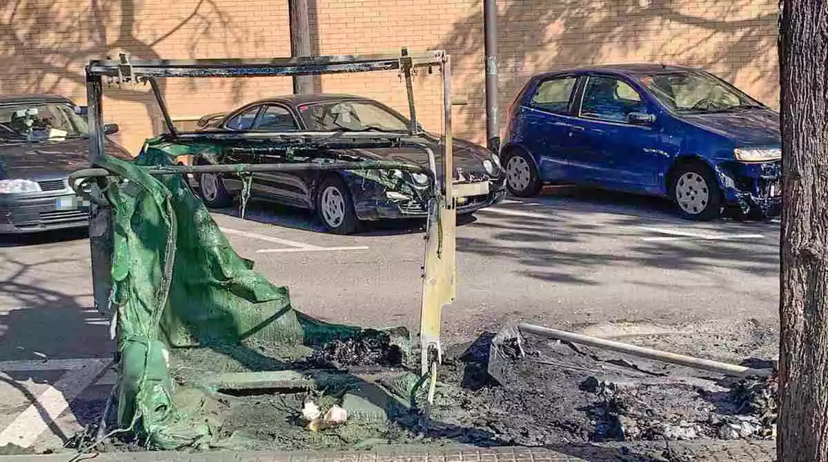 Imatge d'un dels contenidors cremats a Reus i diversos cotxes aparcats afectats pel foc