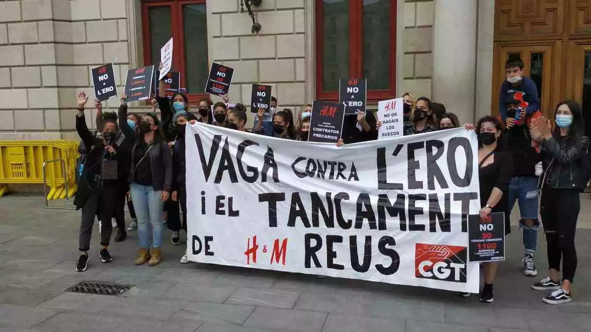 La trentena de treballadores de l'H&M de Reus concentrades davant de la porta de l'Ajuntament amb una pancarta de la CGT on es llegeix «Vaga contra l'ERO i el tancament de H&M Reus»