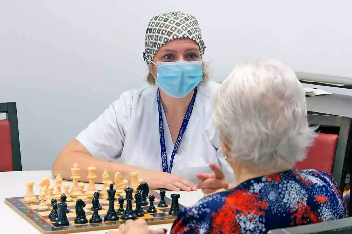 Una sanitària jugant als escacs amb una dona gran
