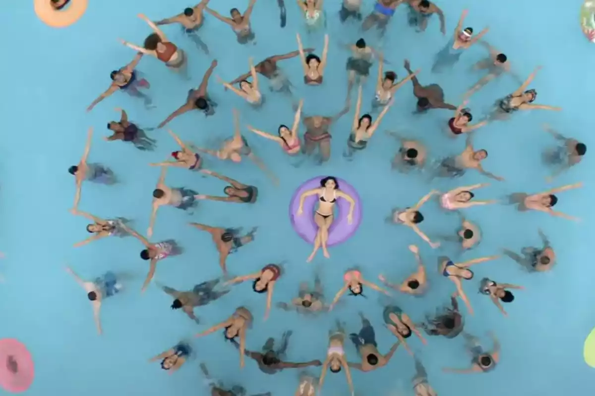 coreografia en una piscina amb diversos ballarins i una noia amb flotador al mig