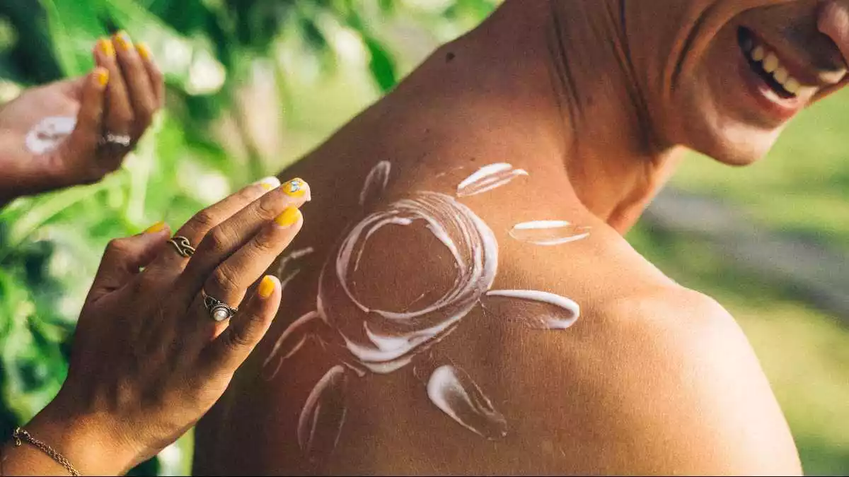 Imatge d'arxiu d'una noia posant crema solar a l'esquena d'un noi