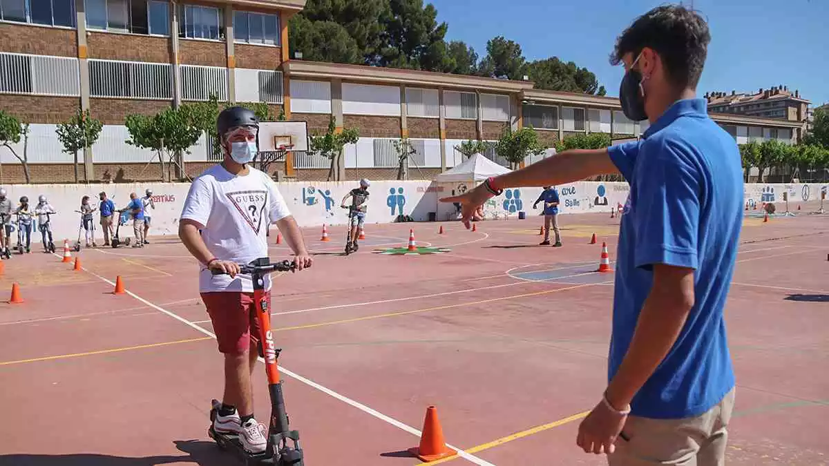 Pla general d'un instructor que dona indicacions a un alumne de batxillerat durant la sessió pràctica de formació en un patinet elèctric a Tarragona