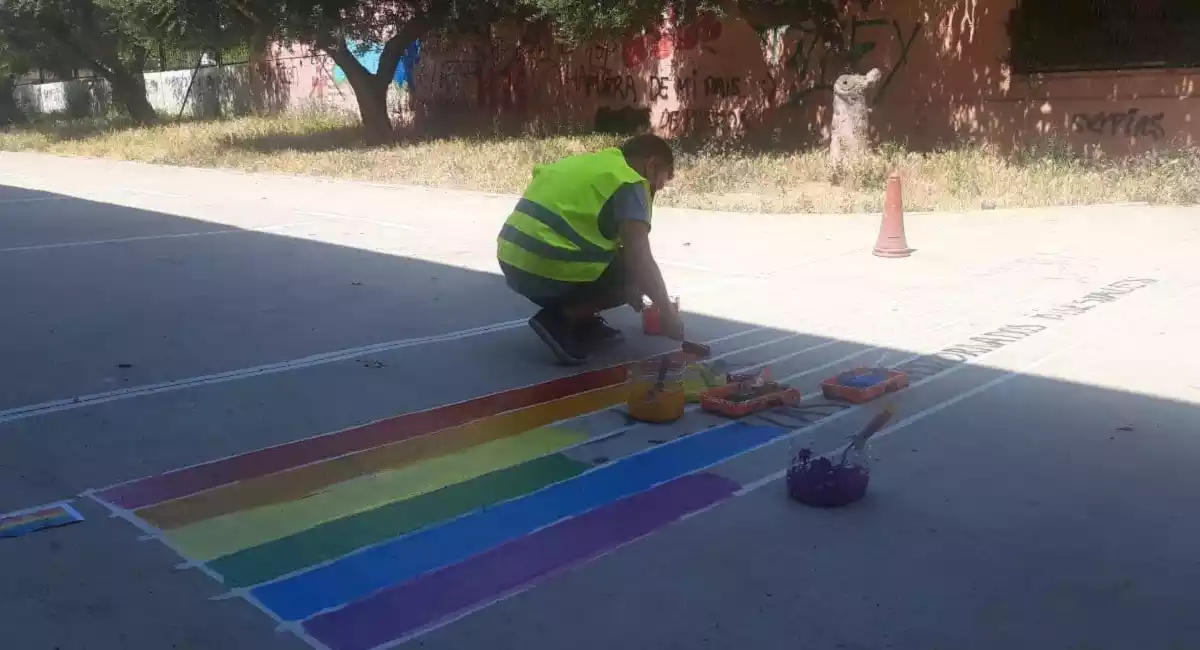 un operari pinta una bandera multicolor a sobre de les pintades homòfobes.