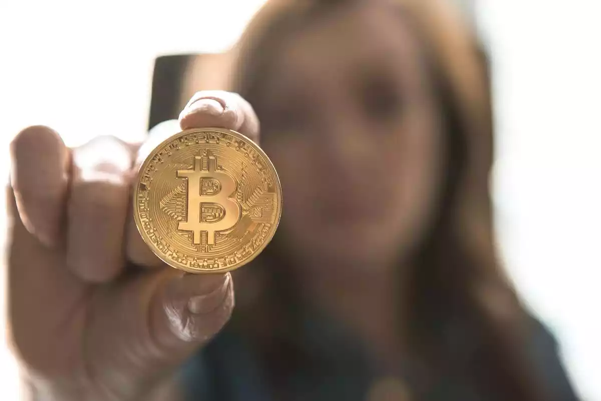 Una dona ensenyant una moneda Bitcoin