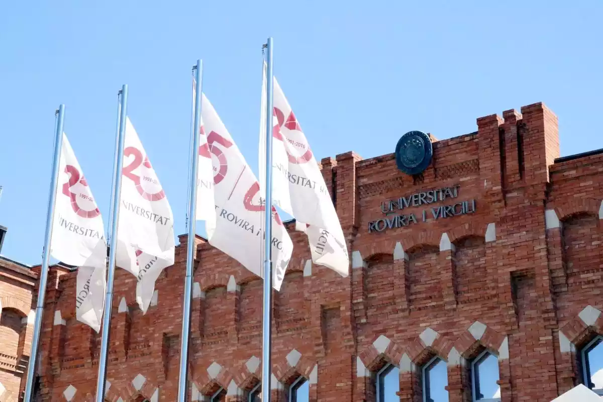 Pla detall de la façana del rectorat de la URV a Tarragona, amb la inscripció de la universitat i diverses banderes