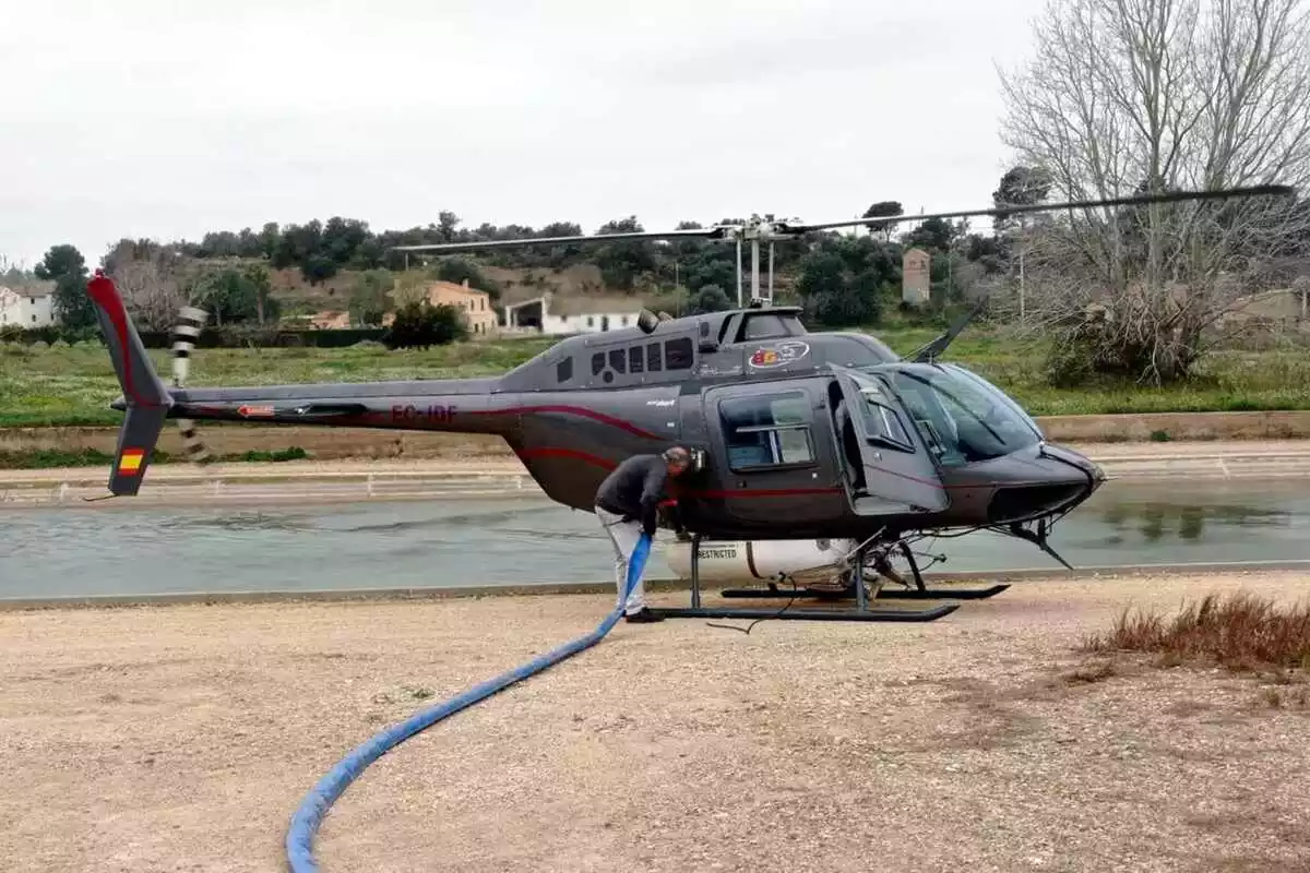 Pla general d'un tècnic carregant el dipòsit de l'helicòpter que fa els tractaments amb BTI contra les larves de mosca negra al riu Ebre