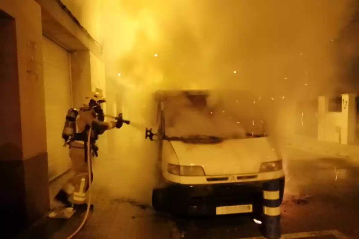 Un bomber apagant les flames que han cremat la furgoneta a Reus