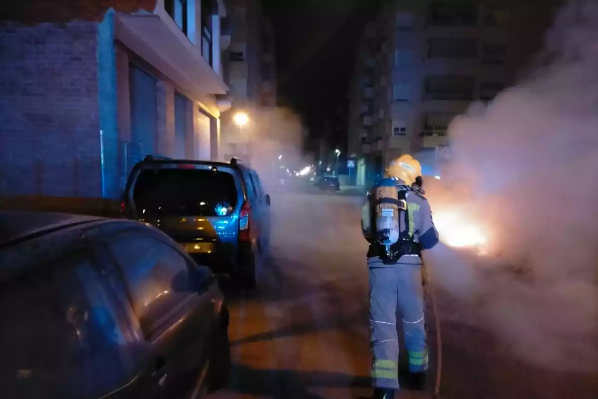 Un bomber apaga les flames d'un dels contenidors cremats al Vendrell