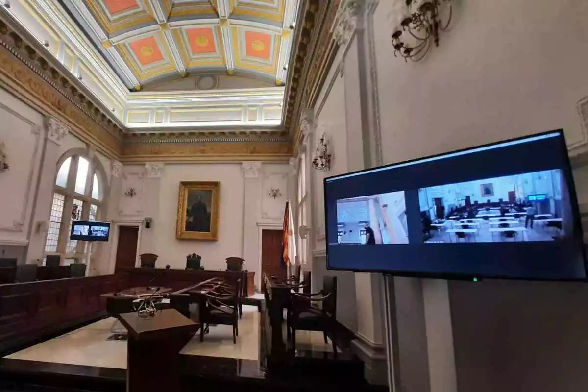 El saló de plens de Reus, amb una pantalla perquè puguin participar els regidors telemàticament