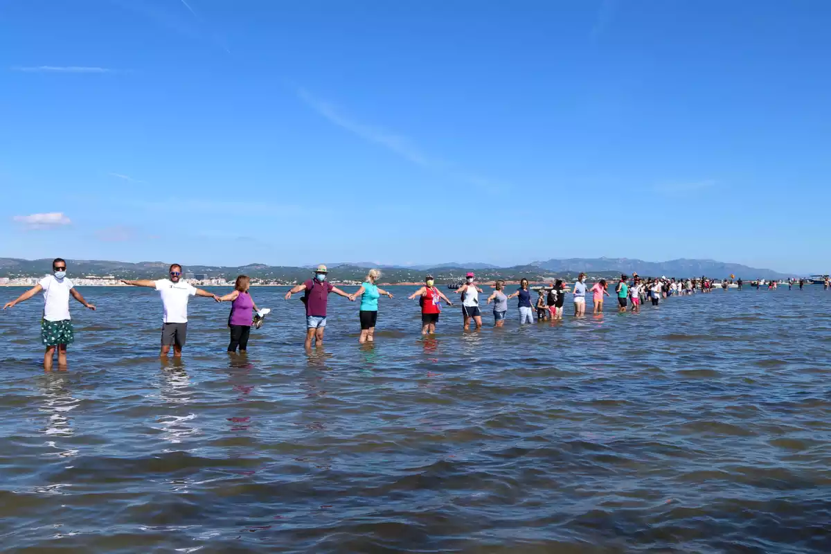 Els participants fent la cadena humana a la badia del Fangar per denunciar la regressió que pateix el delta de l'Ebre