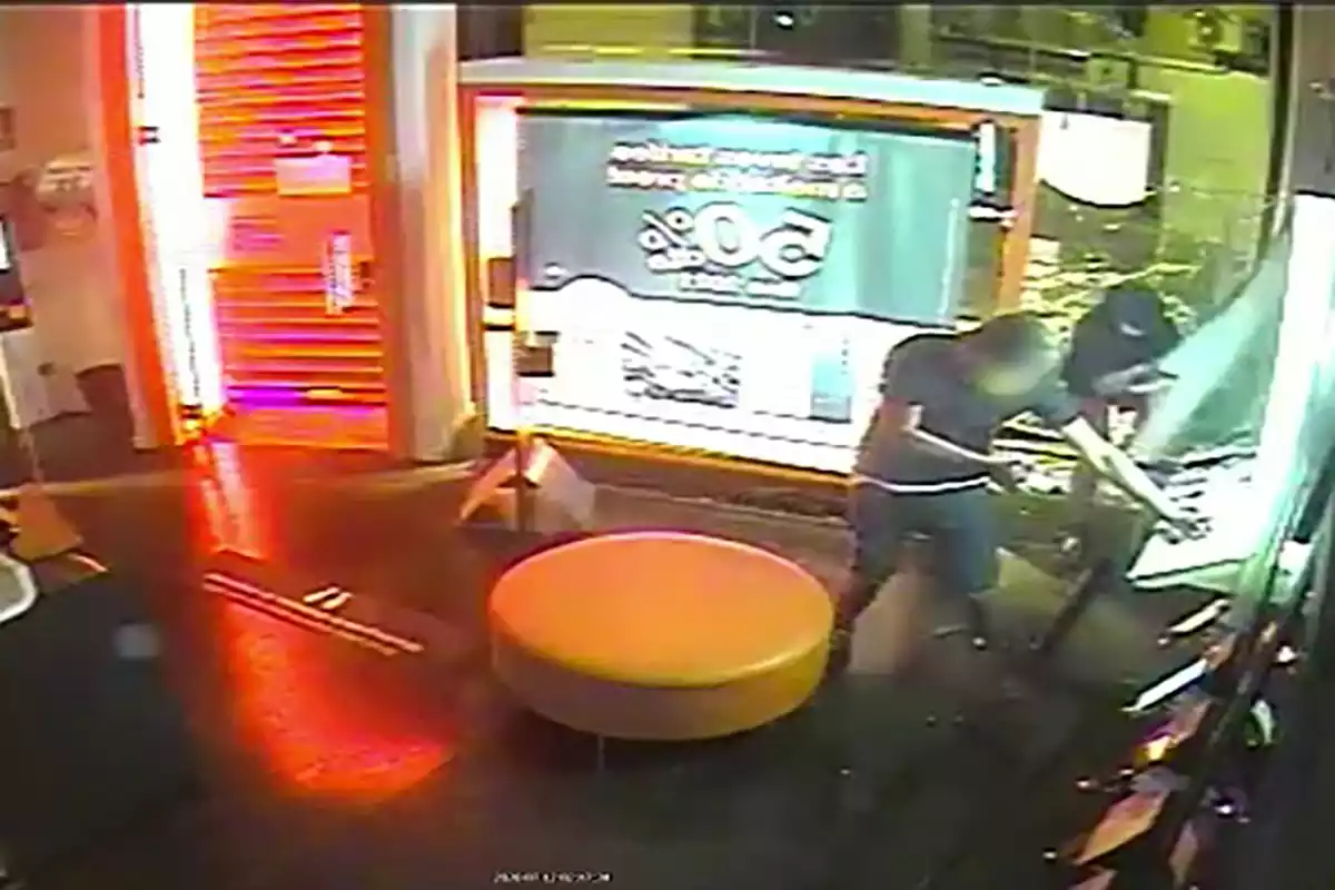 Imatge de dues persones assaltant un local.