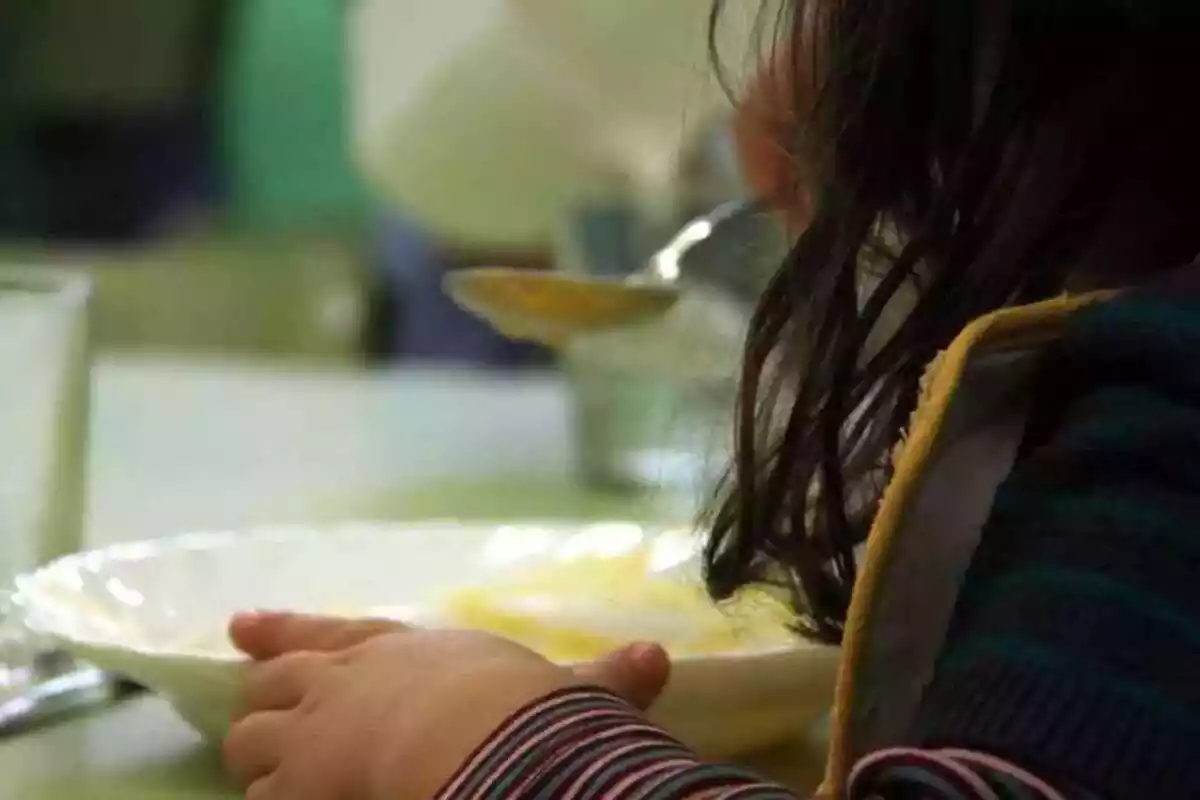Una nena menjant puré en un menjador escolar