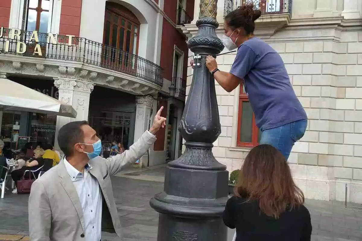 Daniel Rubio assenyala un mesurador de mostra que Anna Ripoll instal·la temporalment en un fanal de la plaça del Mercadal de Reus