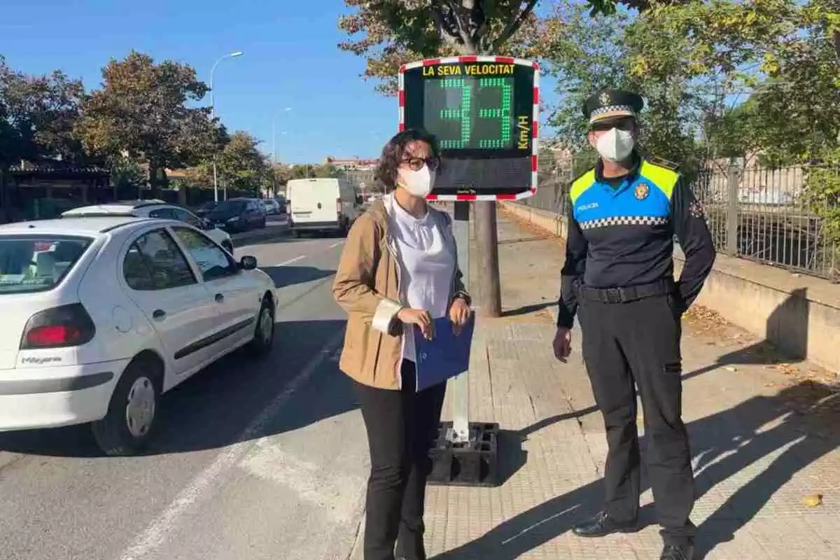 Dolors Vázquez i un agent de la Guàrdia Urbana de Reus davant del radar pedagògic, que mostra la velocitat del cotxe que hi passa