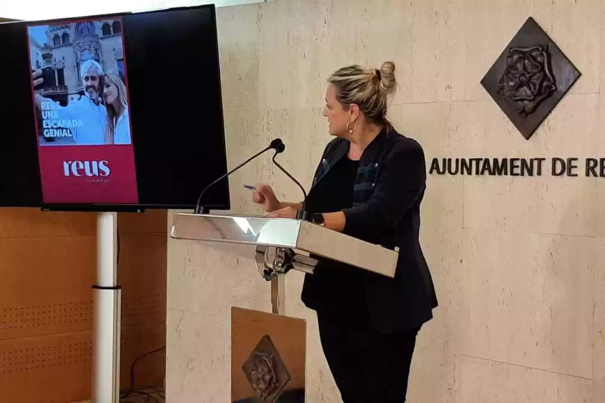 Montserrat Caelles a la sala de premsa de l'Ajuntament de Reus, al costat d'una pantalla amb el cartell de la campanya de tardor