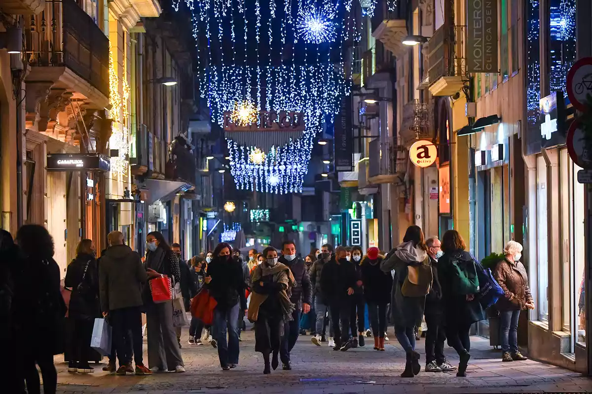 Imatge d'un carrer comercial amb llums de Nadal.
