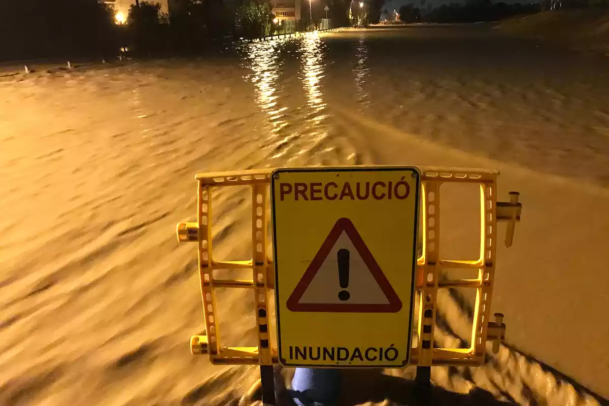 Inundacions a Salou amb un cartell de precaució.