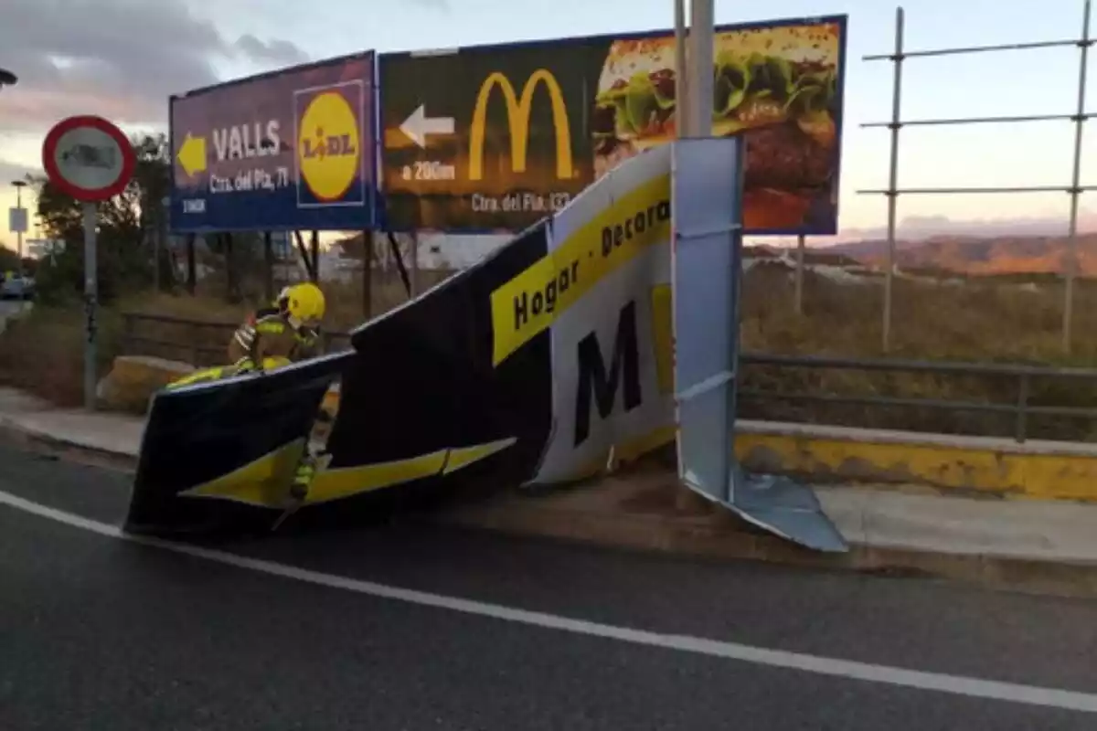 Un cartell publicitari caigut en una carretera a causa del fort vent