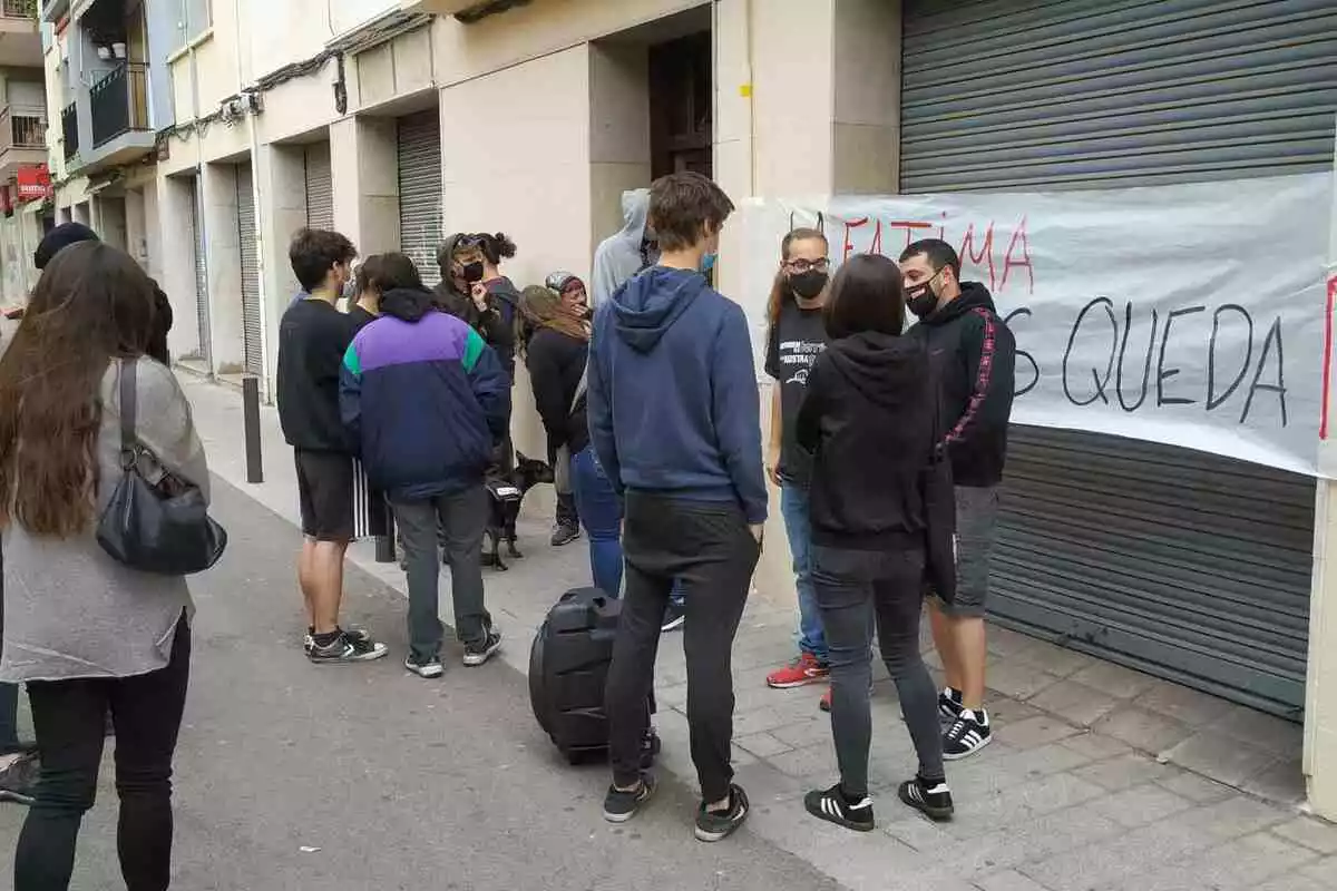 Un grup de concentrats a la porta del bloc on viu Fàtima amb una pancarta donant-li suport