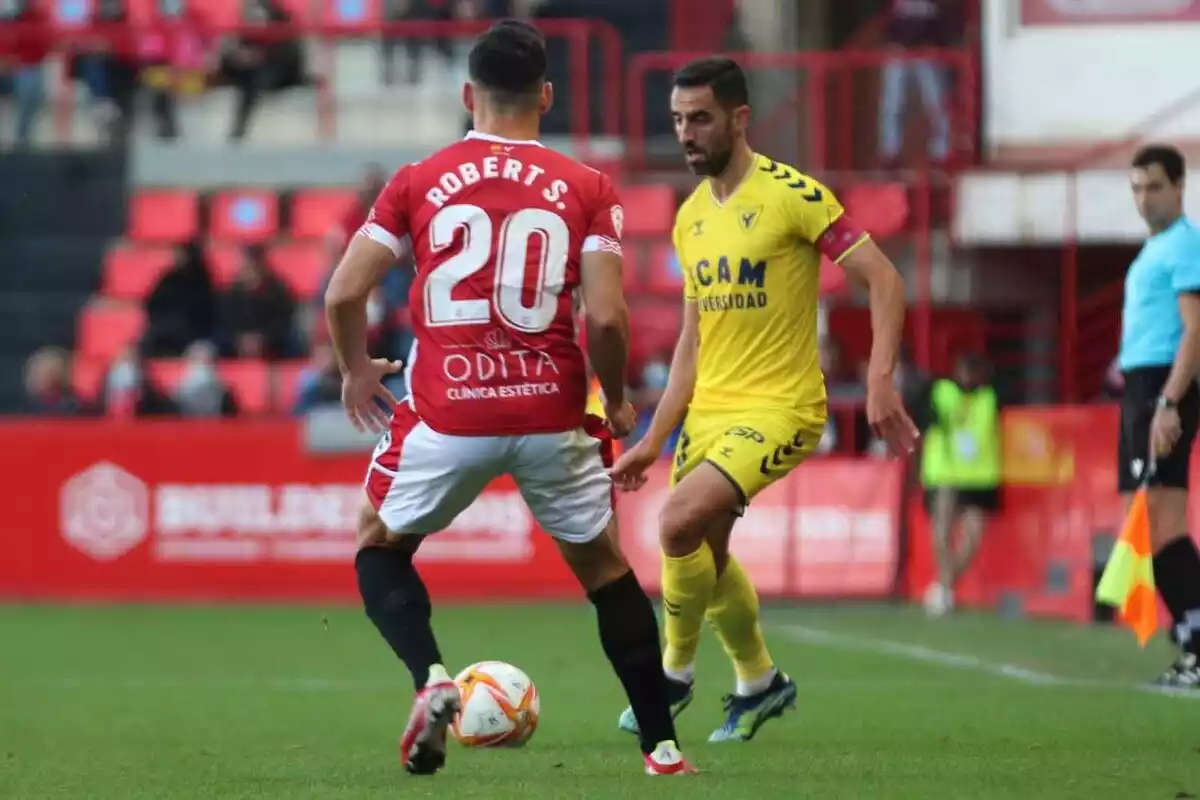 Un jugador de futbol observant un rival mentre controla la pilota