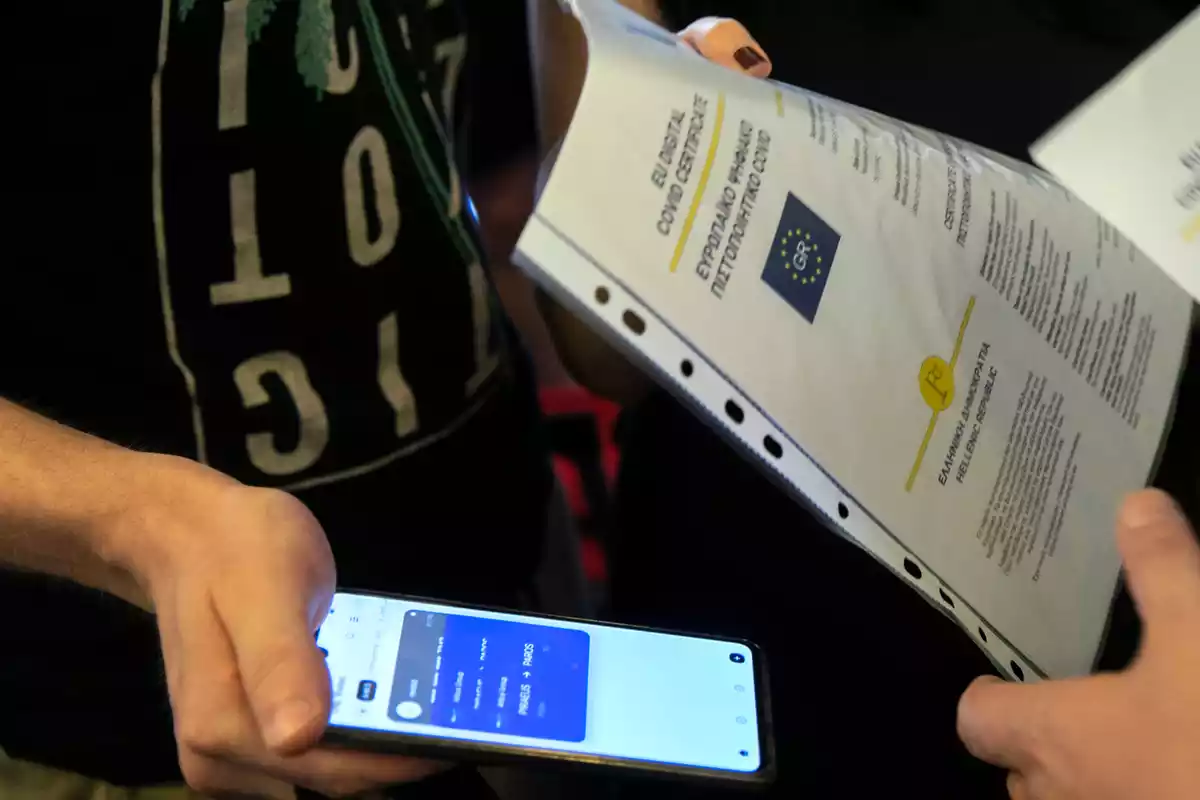 Un membre de la tripulació d’un vaixell que comprova el certificat digital COVID de la UE als passatgers.