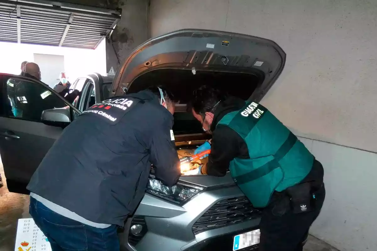 Agents dels Mossos d'Esquadra i de la Guardia Civil inspeccionen un dels vehicles recuperats