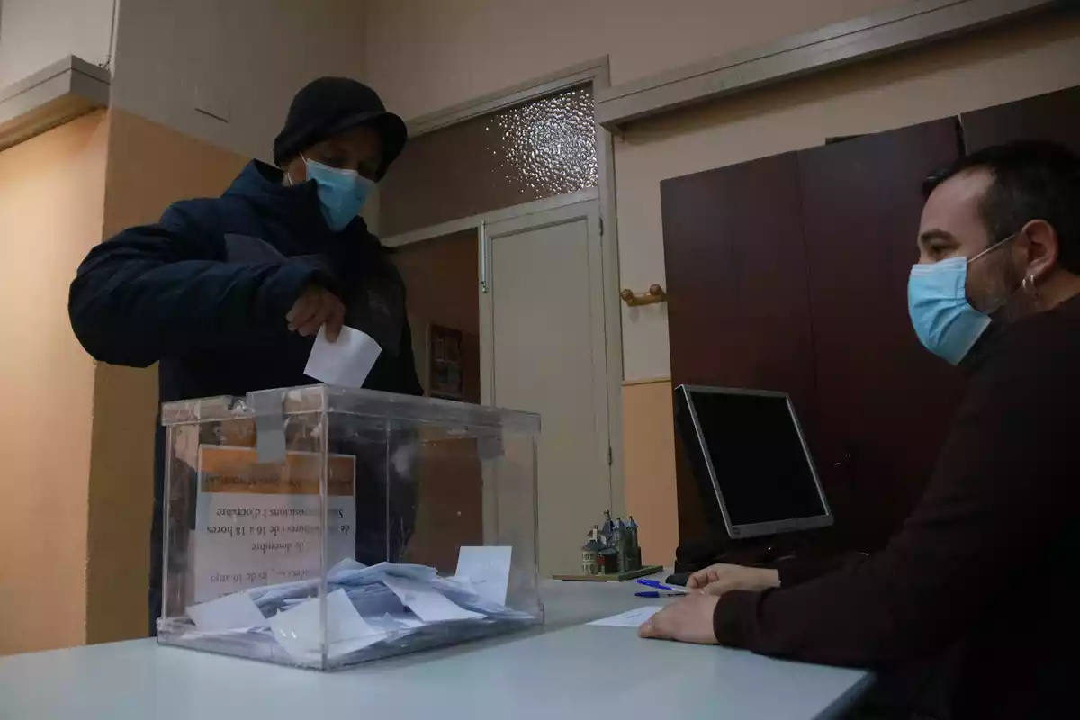 Persona amb una urna introduint el seu vot.