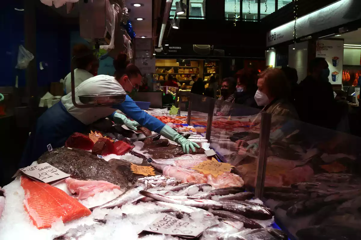 Pla general de venedores i clientes comprant per Nadal en una parada de peix del Mercat Central de Tarragona