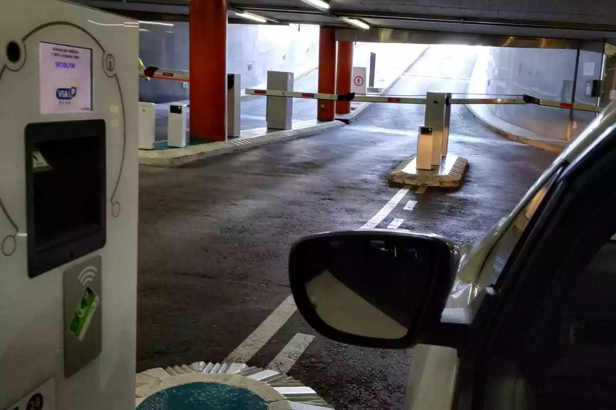 Un cotxe aturat a la sortida d'un aparcament subterrani de Reus, amb l'aparell que regula la barrera informant que s'ha llegit la matrícula