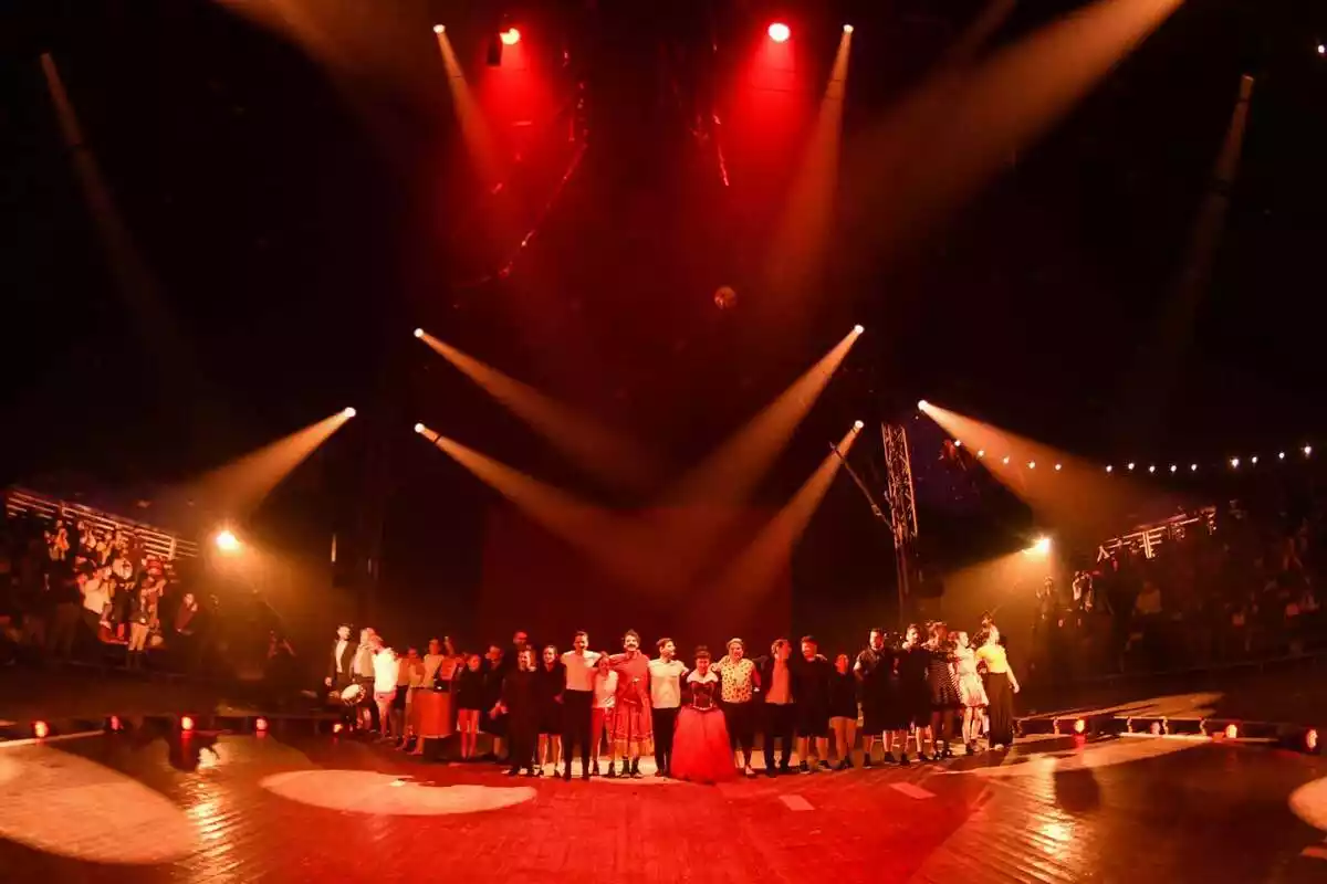 Un nombrós grup d'artistes saluden el públic des de l'escenari d'una carpa de circ
