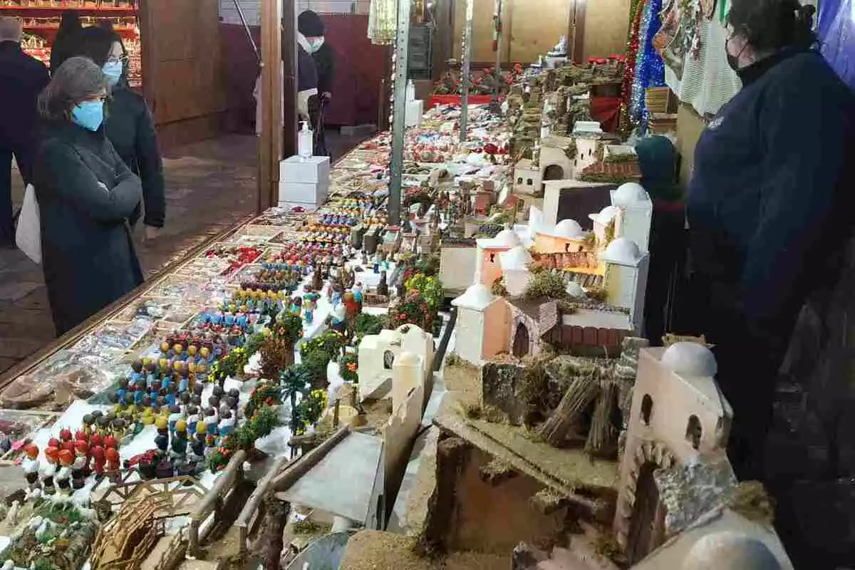 Una parada del Mercat de Nadal de Reus, amb alguns curiosos mirant les figures