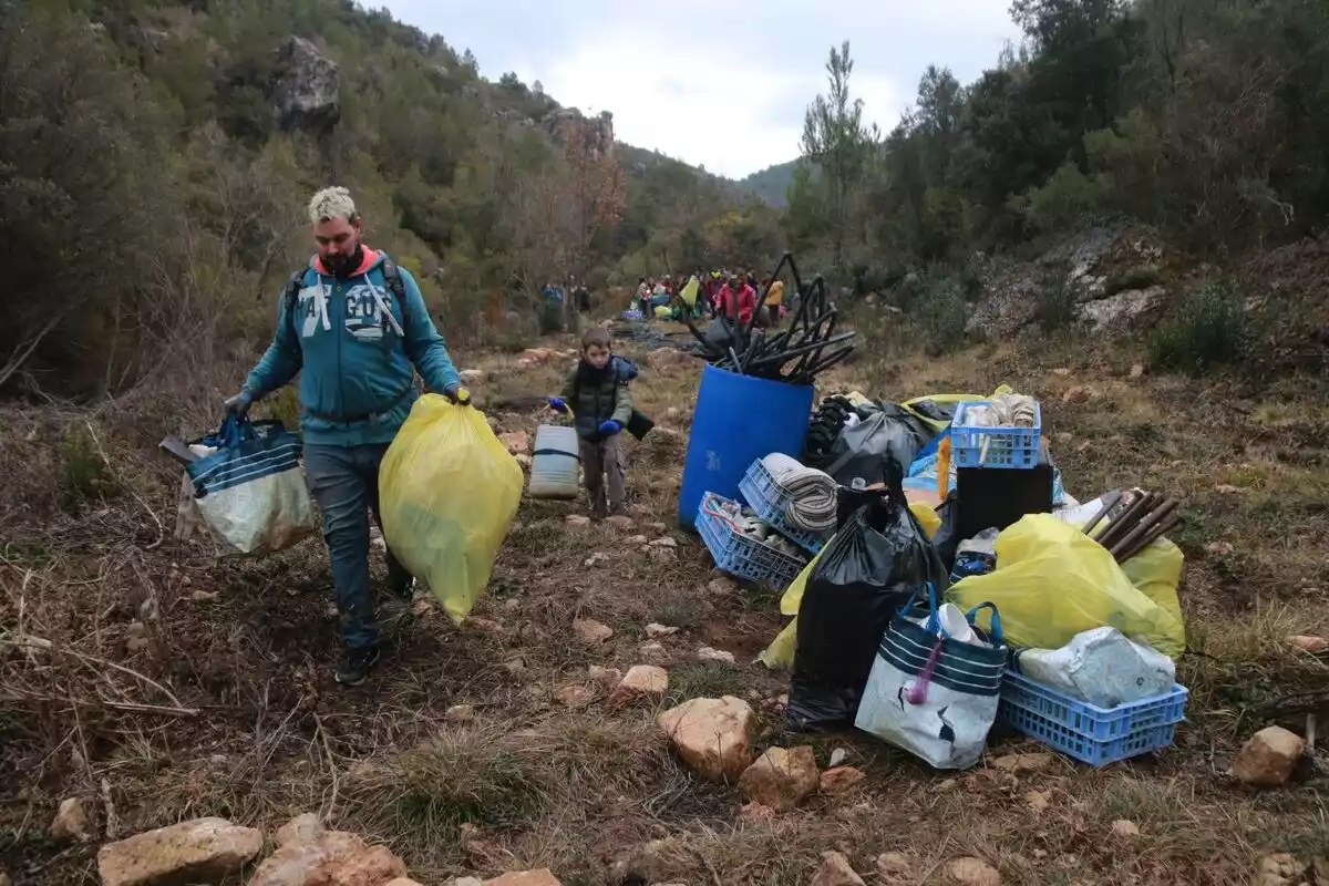 Dos voluntaris retiren deixalles d'una de les plantacions de marihuana desmantellades a Mont-ral