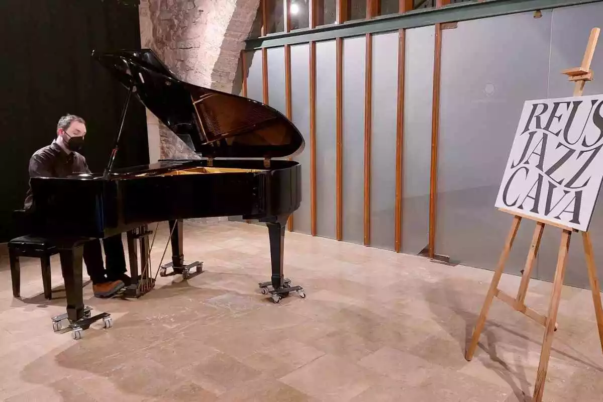 Lluís Capdevila tocant una piano de cua amb el cartell de Reus Jazz Cava al costat