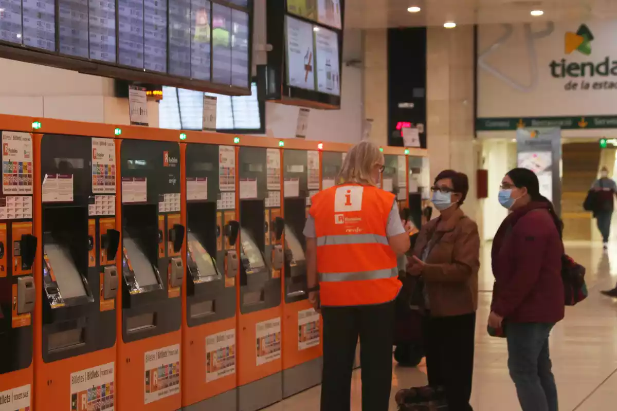Pla obert d'un informador de Renfe ajudant un dels passatgers a l'estació de Sants a Barcelona