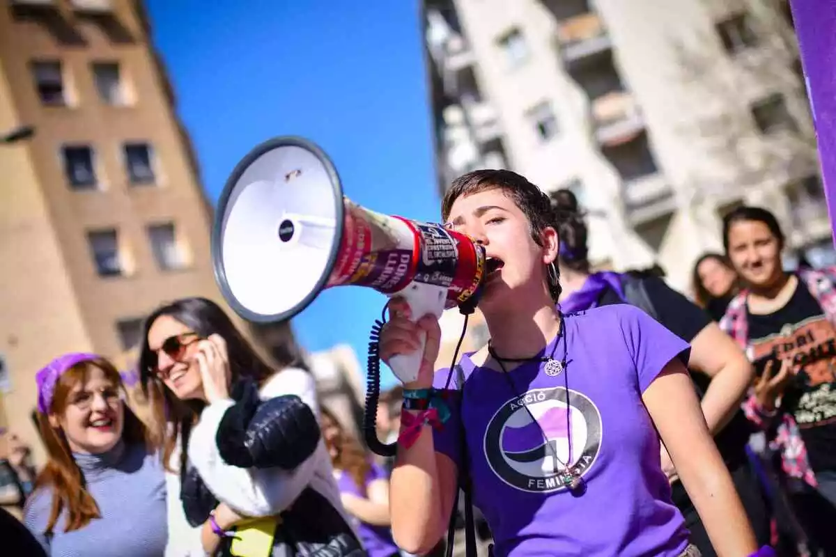 Una noia amb un megàfon durant una manifestació feminista