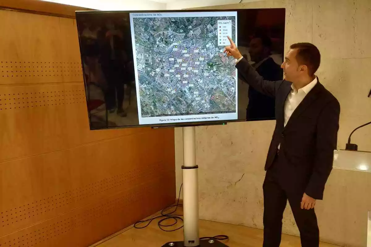 Daniel Rubio, dempeus, assenyala un mapa de Reus en una pantalla a la tarima de la sala de premsa de l'Ajunatment de Reus