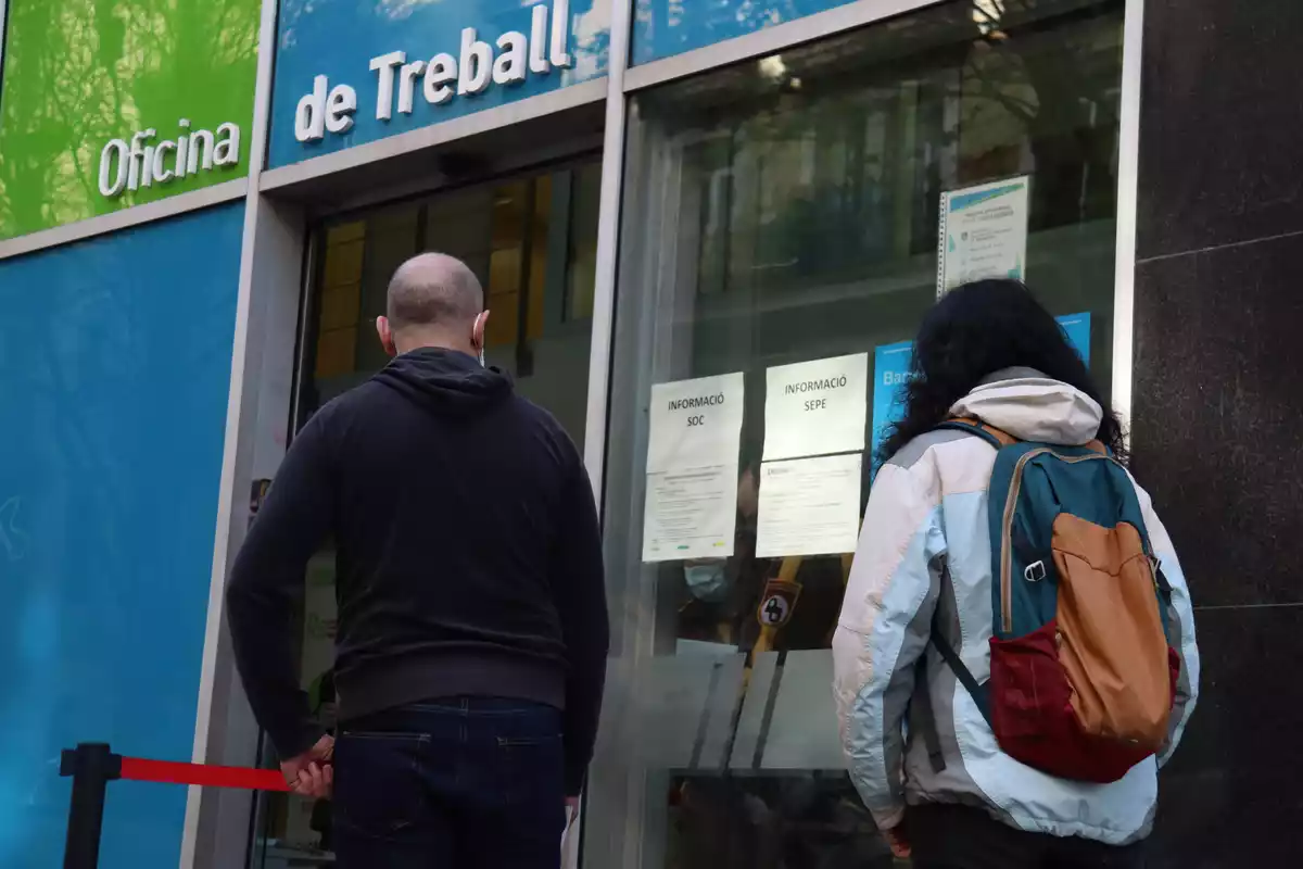 Dues persones esperant per entrar a l'Oficina de Treball del carrer Sepúlveda de Barcelona