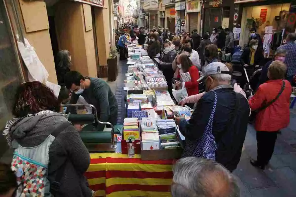 Parades de llibres i persones en un carrer per Sant Jordi