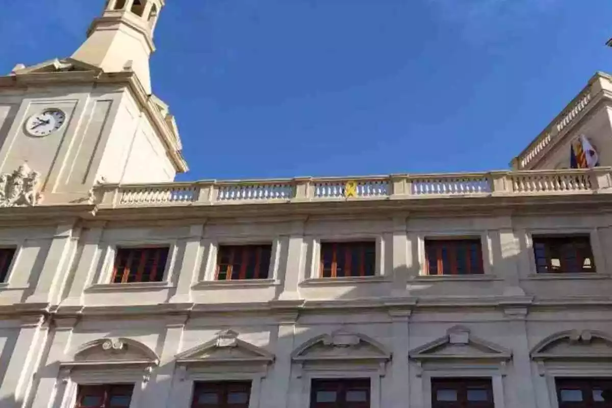 Part superior de la façana principal de l'Ajuntament de Reus, amb el llaç groc penjat al centre de la barana del terrat
