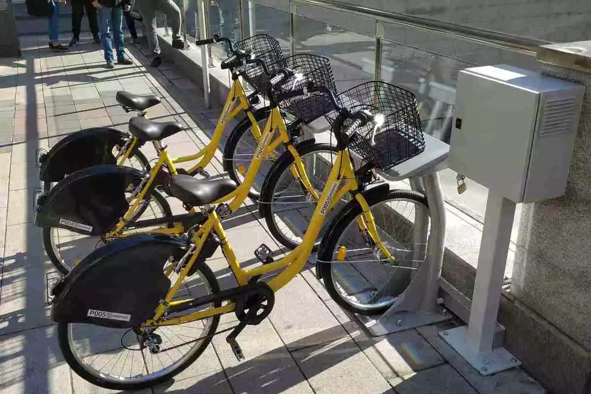 Tres bicicletes grogues ancorades als punts d'aparcament de la prova pilot del sistema de bicicleta pública compartida de Reus