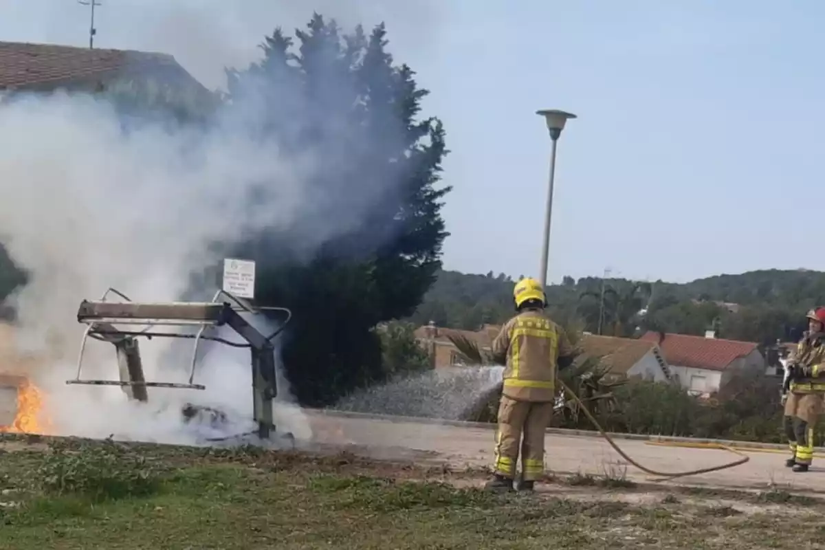 Un Bombers apagant un incendi d'un contenidor.