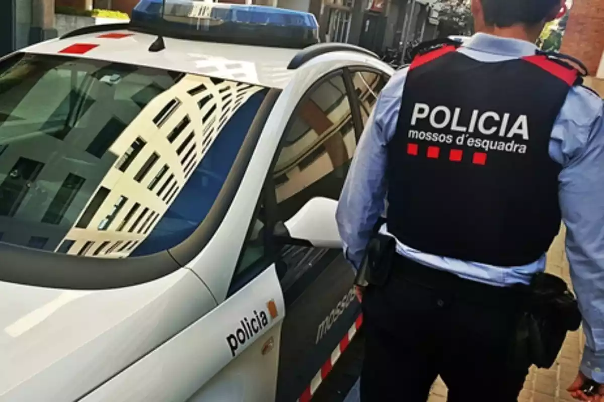 Un agent dels Mossos d'Esquadra al costat d'un vehicle del cos policial