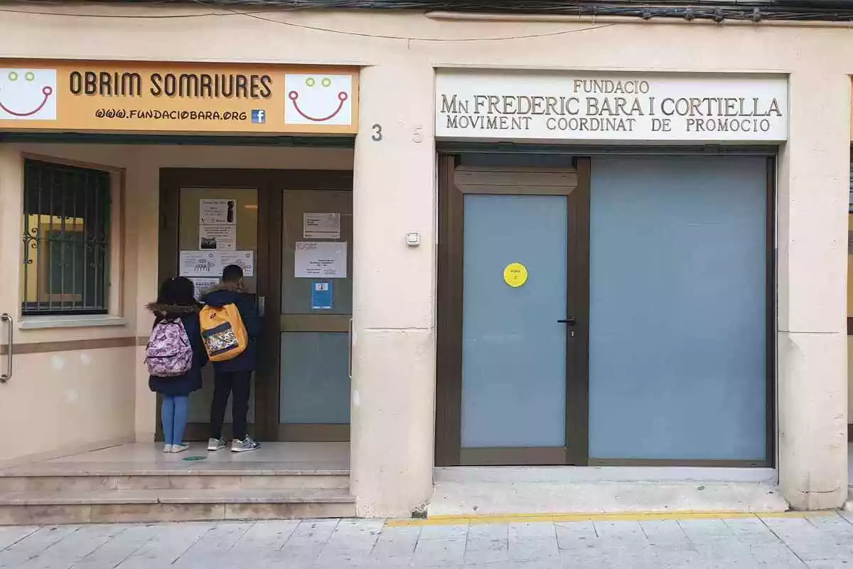Façana principal de la Fundació Mossèn Frederic Bara, amb dos infants a la porta