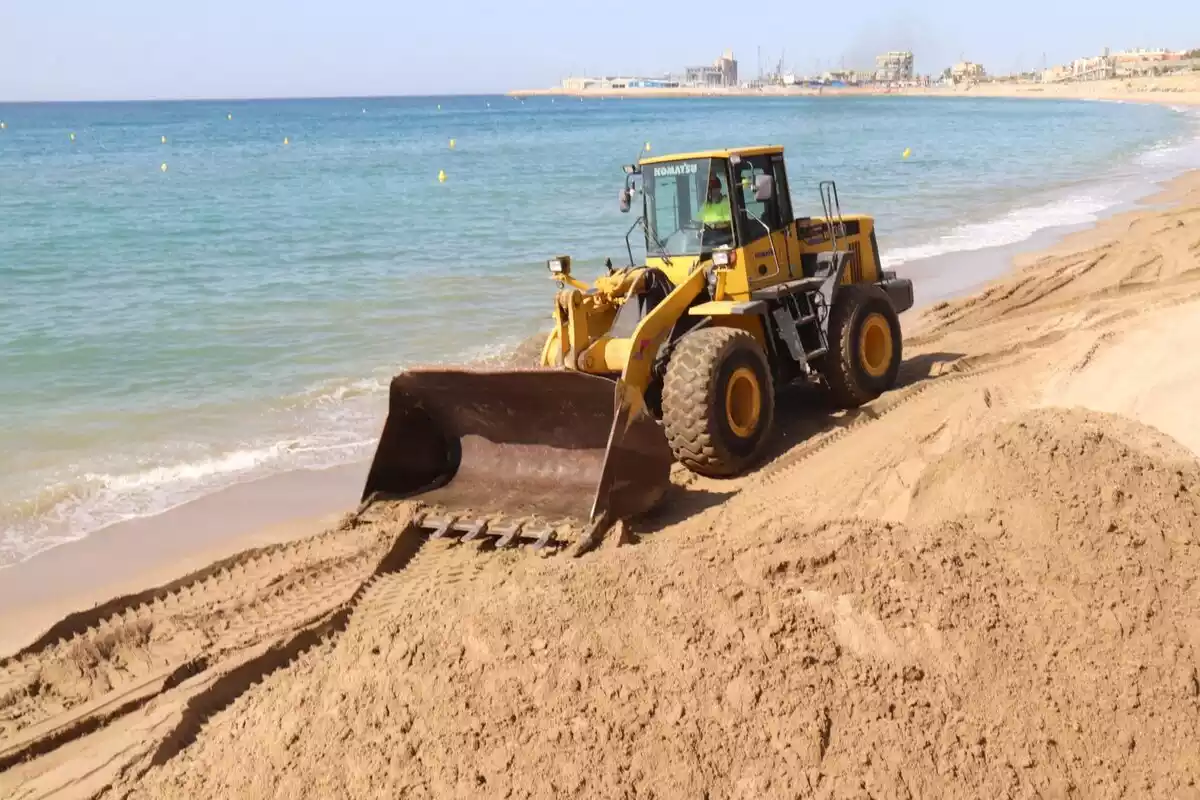 Imatge d'una màquina abocant sorra a la platja del Miracle de Tarragona