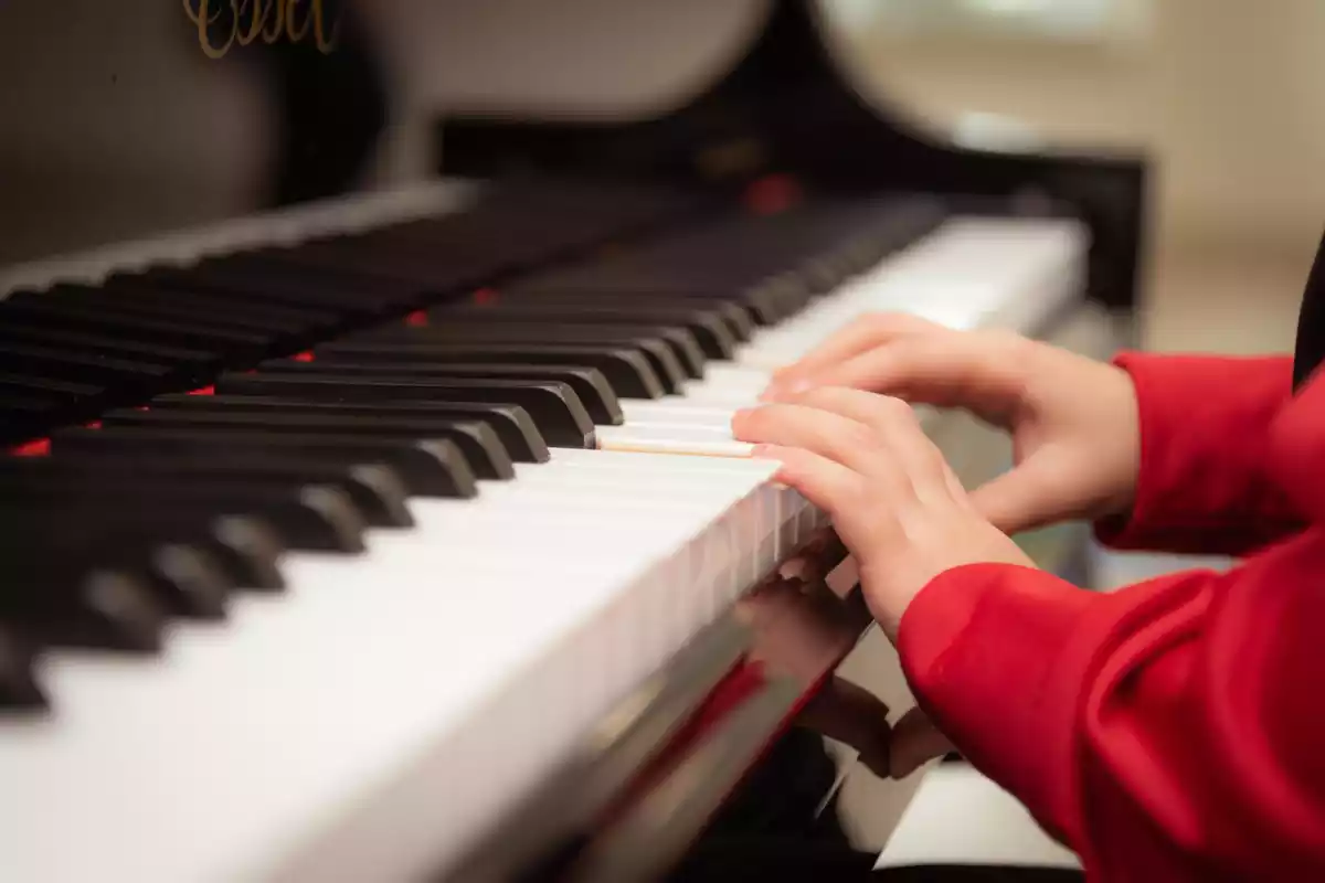 Imatge d'unes mans de nen tocant les tecles d'un piano