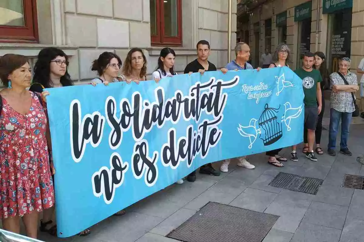 Membres de la CUP i acompanyants dels imputats mostren una pancarta amb el lema 'La solidaritat no és delicte'