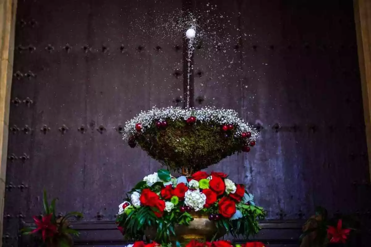 Una font guarnida amb flors, a la plaça del Castell de Reus, amb un ou ballant al capdamunt del doll d'aigua