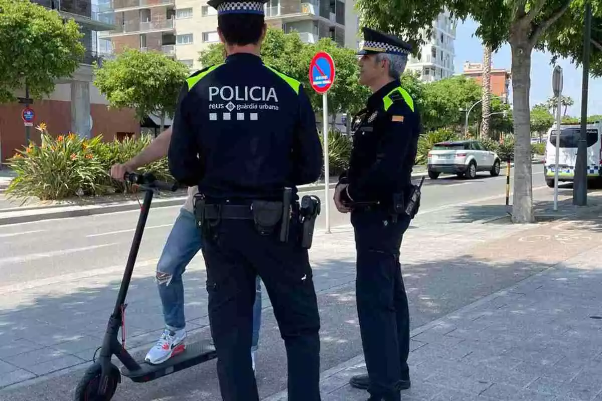 Dos agents de la Guàrdia Urbana de Reus aturen i parlen amb l'usuari d'un patinet elèctrics
