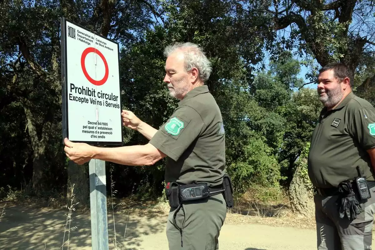 Imatge de dos agents rurals senyalitzant la prohibició d'accedir a un espai natural