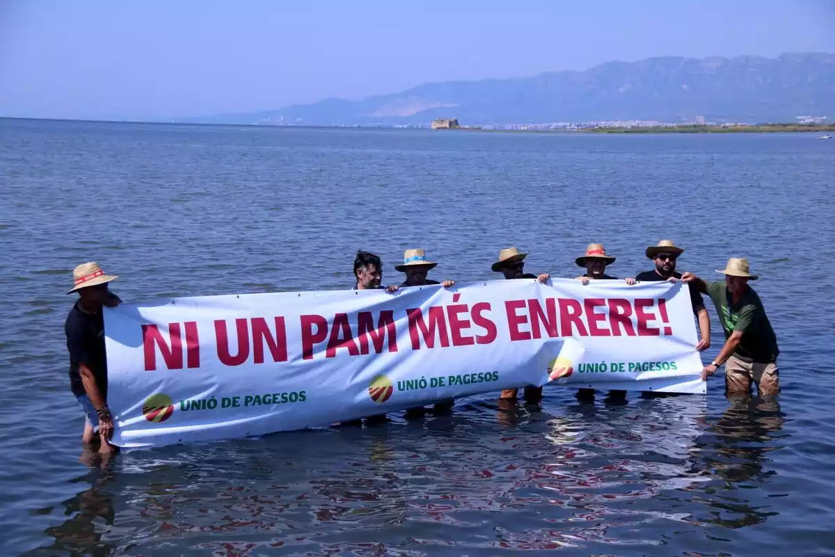 Representants d'Unió de Pagesos subjectant una pancarta a la badia dels Alfacs en l'acció per denunciar la regressió del Delta de l'Ebre
